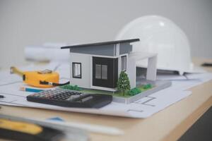 A small model of a house sits on top of a desk photo