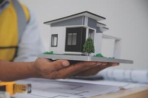 A man holding a model of a house on a table photo