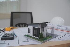 A model of a house on a desk with a calculator and other items photo