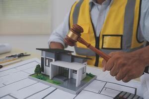 A man holding a gavel and looking at a model house photo