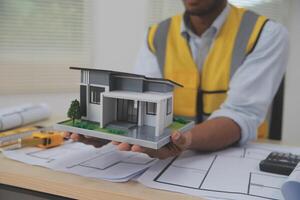 A man holding a model of a house on a desk photo