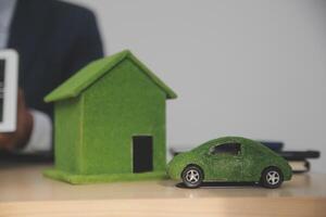 A man in a suit is holding a tablet computer and a small car on a desk photo