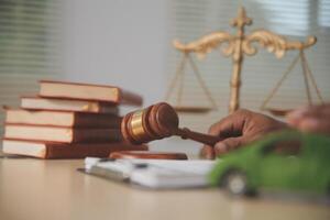 A car and a gavel on a desk with books and a scale of justice photo
