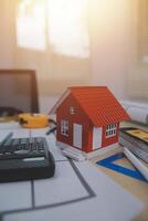 A house model sits on a desk with a calculator and a calculator photo