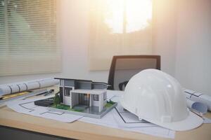 A hard hat and a model of a house on a desk photo