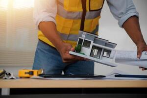 A man holding a model of a house on a table photo