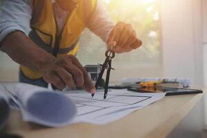 A man in a hard hat and vest is working on a blueprint photo