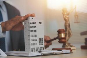 A man in a suit holding a model of a building and a gavel photo