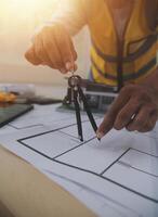 A man in a yellow vest and hard hat is working on a blueprint photo