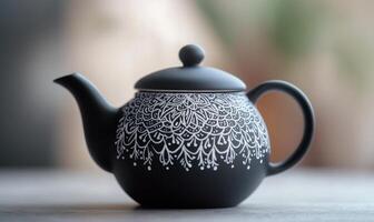 a black teapot with white designs on it photo
