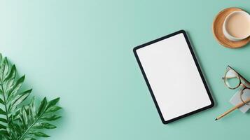 A tablet sits on a table next to a cup of coffee and a pair of glasses photo