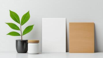 A white frame sits on a table next to a potted plant and a jar photo
