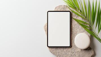 A tablet is sitting on a rock with a leaf on top of it photo