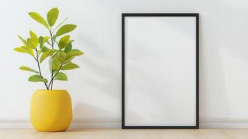 A yellow vase with a plant in it sits on a wooden table next to a black frame photo