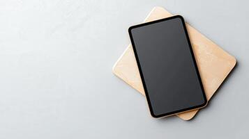 A black tablet sits on a wooden surface photo