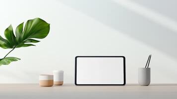 A tablet sits on a table next to a plant and a cup photo