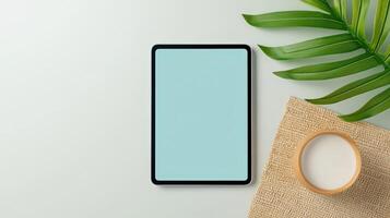 A tablet is sitting on a table next to a cup of milk photo