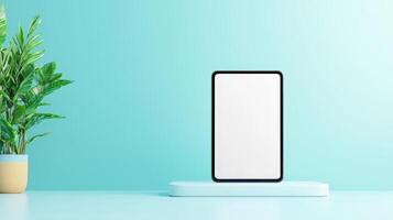 A white tablet sits on a pedestal in front of a green plant photo