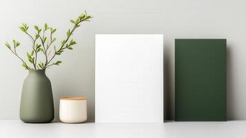 A white frame sits on a table next to a vase and a green box photo