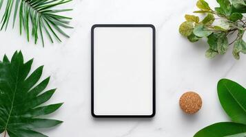 A tablet is sitting on a table with a leafy green background photo