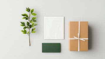 A box with a white ribbon sits on a table with a green leaf and a white card photo