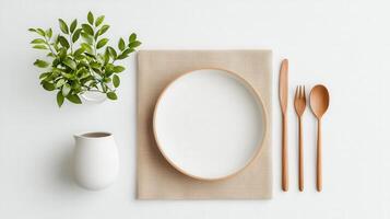 A white plate with a fork and spoon on a table with a plant in a vase photo