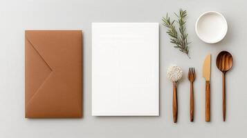 A white card with a brown envelope and a knife, fork, and spoon on top of it photo