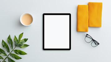 A tablet sits on a table with a cup of coffee and a pair of glasses photo