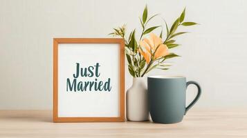 A framed sign that says Just Married sits on a table next to a vase of flowers photo