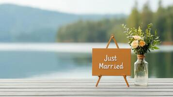 A wooden sign that says Just Married is placed on a wooden table next to a vas photo
