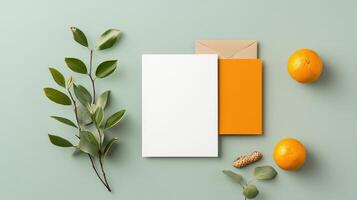 A white card with a leaf on it is on a table with an orange and a card photo