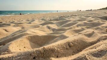 Golden Beach Sand Texture at Sunny Seaside, Coastal Landscape with Gentle Waves and Distant Figures photo