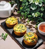 Savory mini quiches with spinach and herbs on a rustic table photo