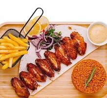 Spicy grilled chicken wings served with fries and rice photo