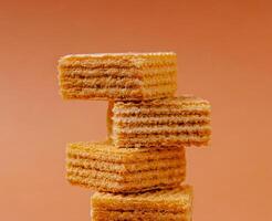 Layers of crispy wafers stacked against a soft orange background photo