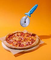 Perfectly cooked pepperoni pizza with a pizza cutter above it photo