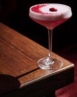 Elegant cocktail garnished with raspberry on a wooden table photo