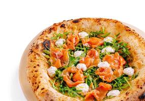 Savory pizza topped with smoked salmon and arugula on a rustic plate photo