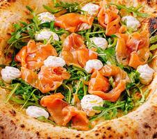 Fresh smoked salmon and arugula salad served in a crispy pizza photo