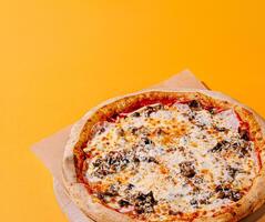 Pizza with mushrooms on an orange background photo