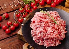 Fresh ground meat prepared for cooking with cherry tomatoes photo