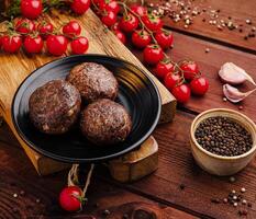 Juicy meatballs with fresh tomatoes and spices on wooden table photo