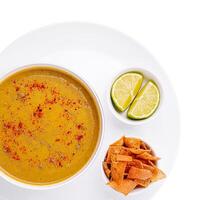 Delicious bowl of nutritious soup with lime and crispy chips photo