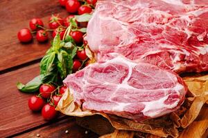 Fresh meat cuts with cherry tomatoes and basil on wooden surface photo
