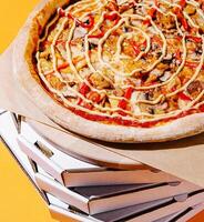Delicious pizza topped with vegetables on a stack of boxes photo