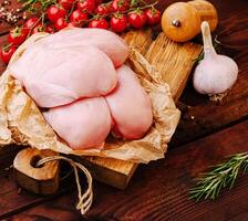 Fresh chicken meat with garlic and cherry tomatoes on wooden table photo