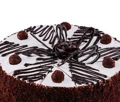 Chocolate cake with white icing being decorated with chocolate sauce photo