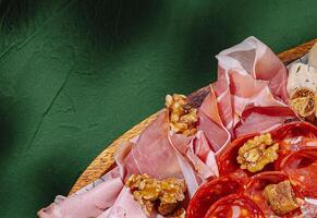 Charcuterie board with meats and nuts on a green background photo