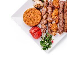 Savory grilled meats with rice and fresh vegetables on a plate photo