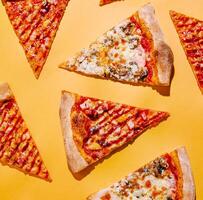 Slices of pizza arranged on a bright yellow background photo